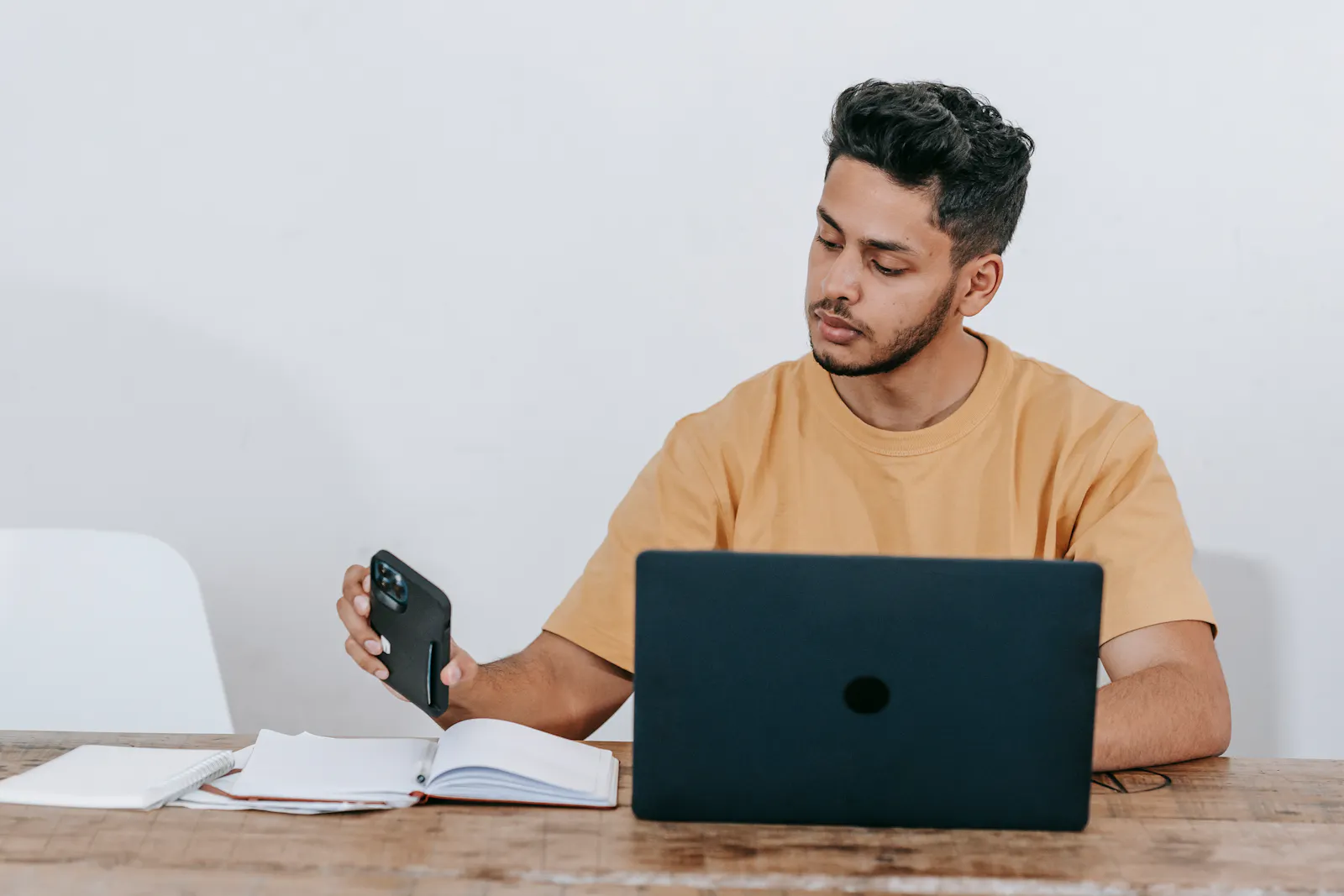 Profissional usando celular e laptop para organizar demandas de trabalho