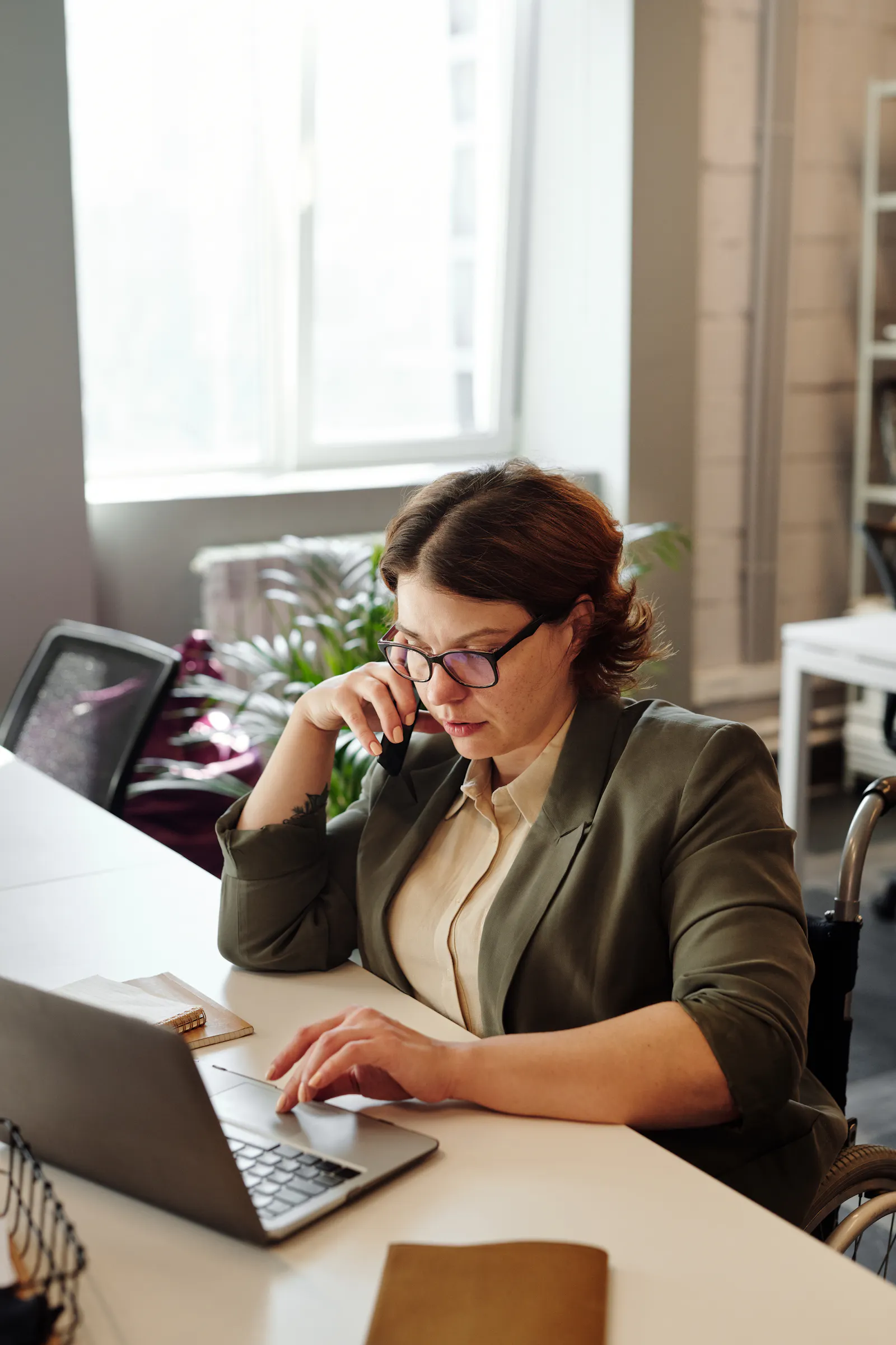 Profissional usando celular e laptop para atender clientes e organizar demandas